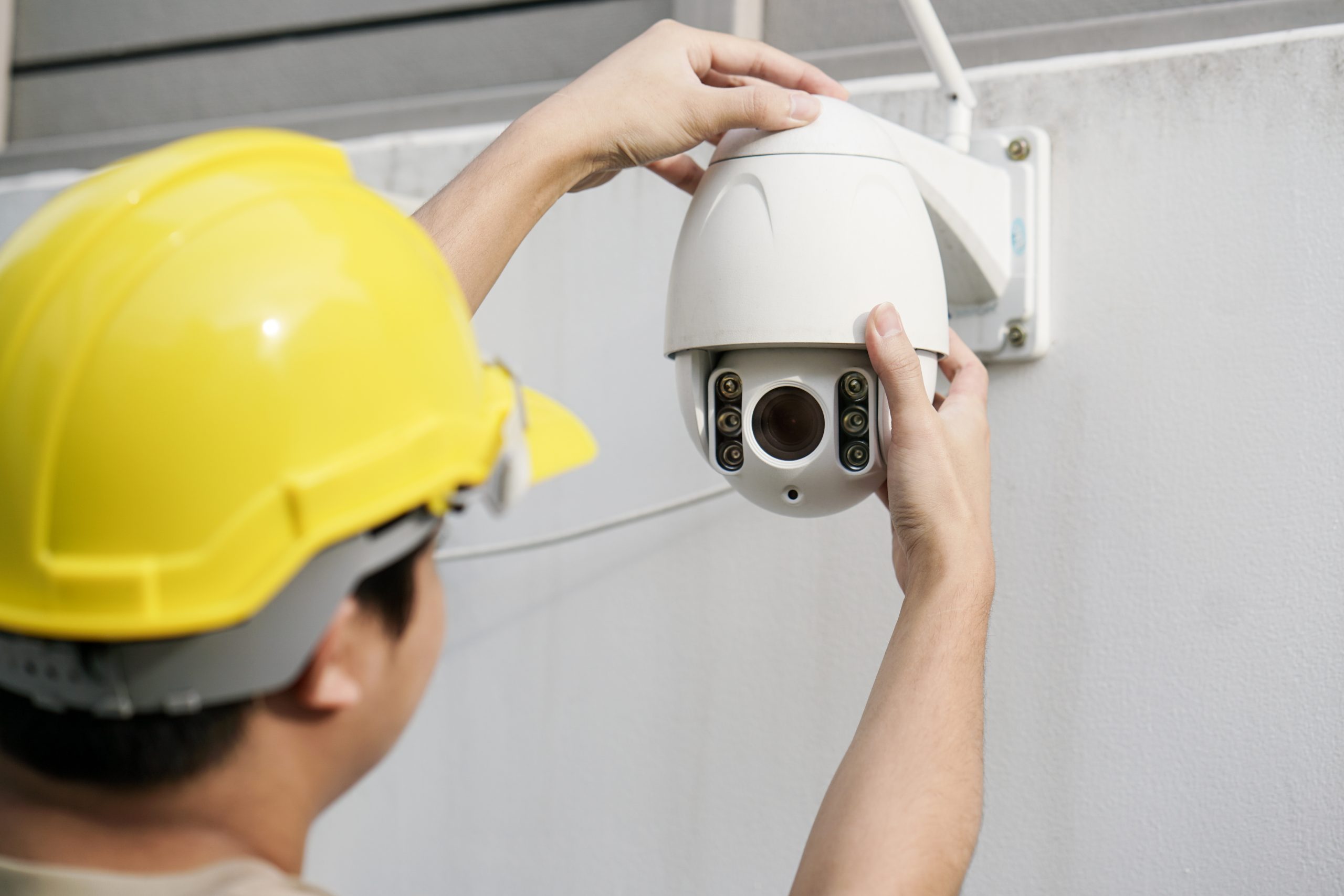 Close Up Of Male Technician Fixing CCTV Camera On Wall